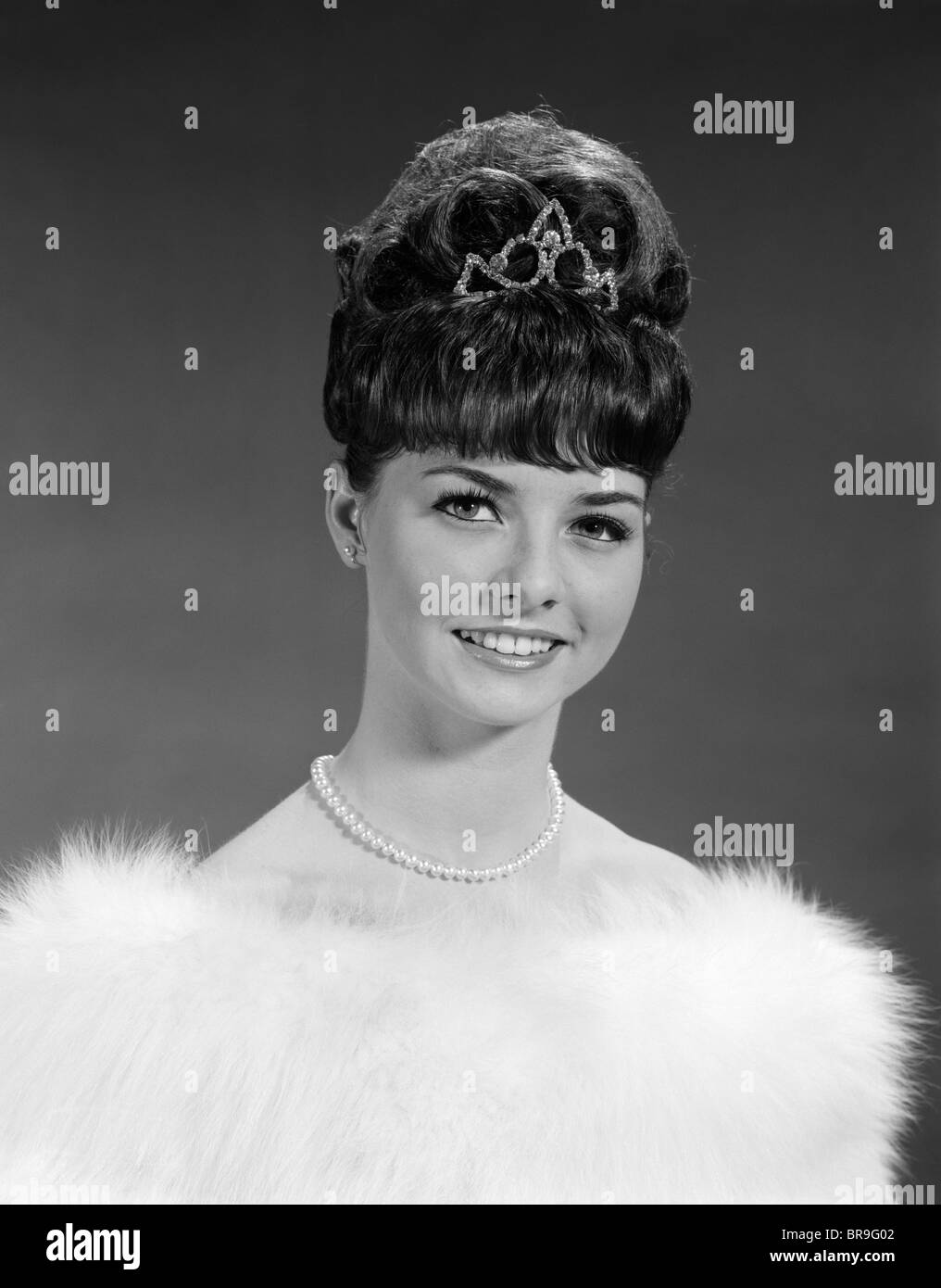1960s PRETTY YOUNG WOMAN WEARING TIARA FUR STOLE AND STRING OF PEARLS LOOKING AT CAMERA Stock Photo