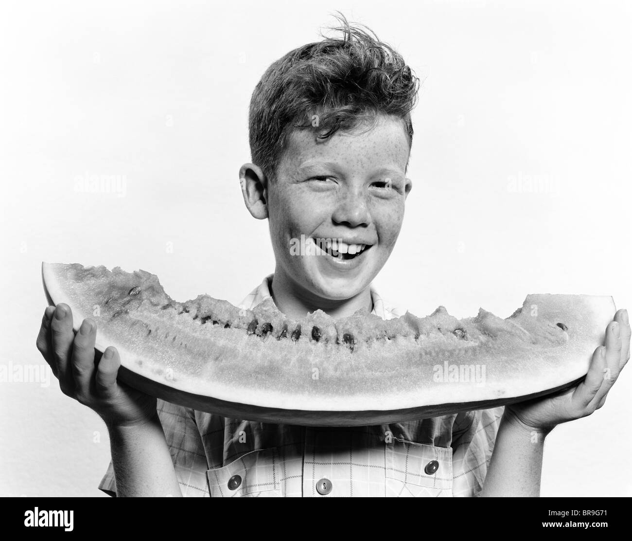 1940s 1950s SMILING BOY HOLDING EATING LARGE SLICE OF WATERMELON Stock Photo