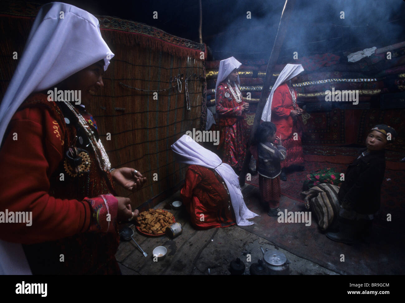 Kyrgyz women in traditional dress do chores inside a yurt at a nomad camp in the Little Pamirs Wakhan Corridor. Stock Photo