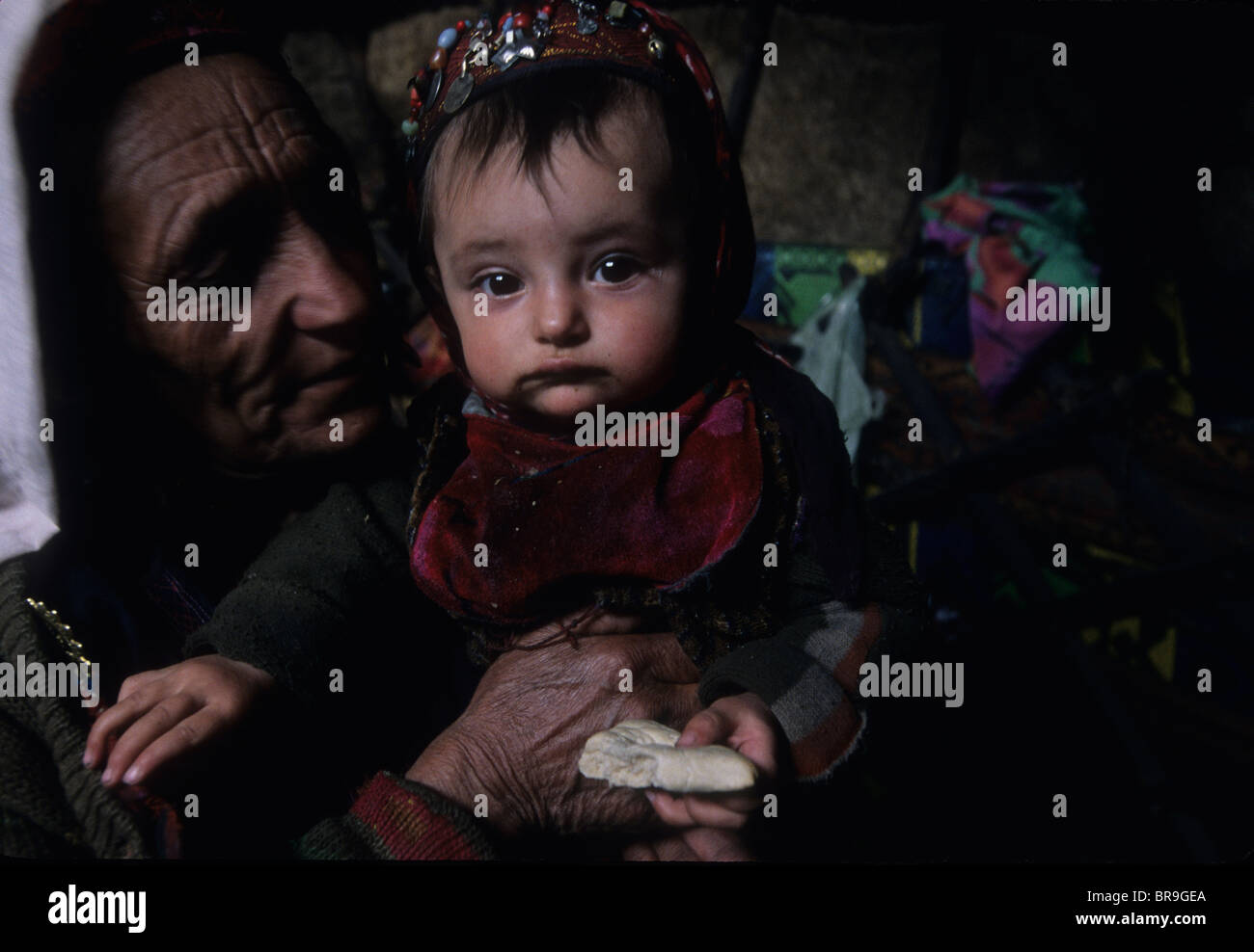 A woman of the Wakhi tribe holds a young child in a shepherds' camp in the Big Pamirs Wakhan Corridor Badakshan Stock Photo