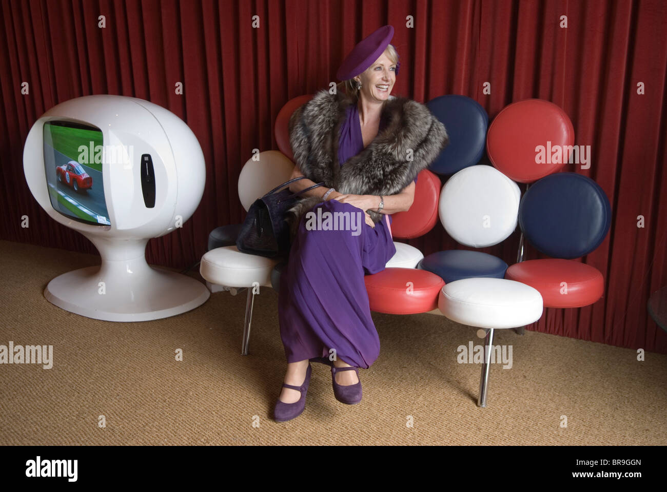 Retro woman dressed up in fashionable 1950s 1940s style at the  Goodwood Festival of Speed. Goodwood Sussex UK. VIP lounge, vintage chair and TV.   2010 2010s HOMER SYKES Stock Photo