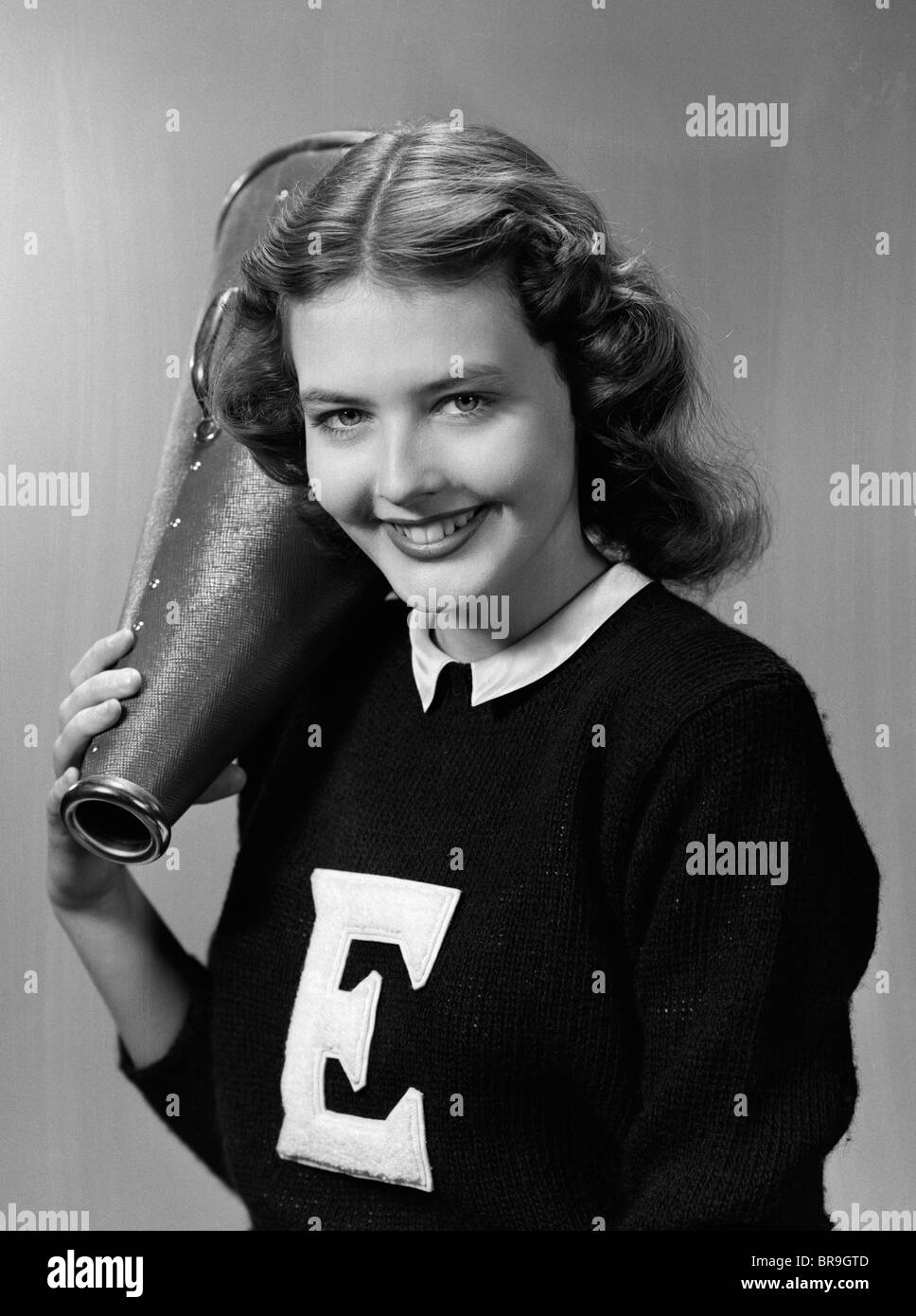 1940s 1950s GIRL CHEERLEADER WITH MEGAPHONE SMILING LOOKING AT CAMERA Stock Photo