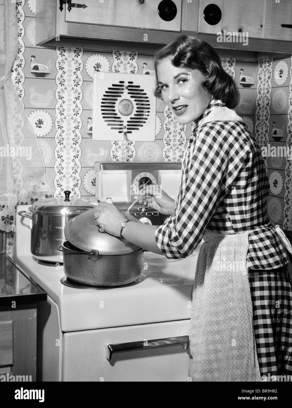 1950s HOUSEWIFE WEARING CHECKERED DRESS STANDING IN KITCHEN STIRRING POT ON  STOVE LOOKING OVER SHOULDER Stock Photo - Alamy