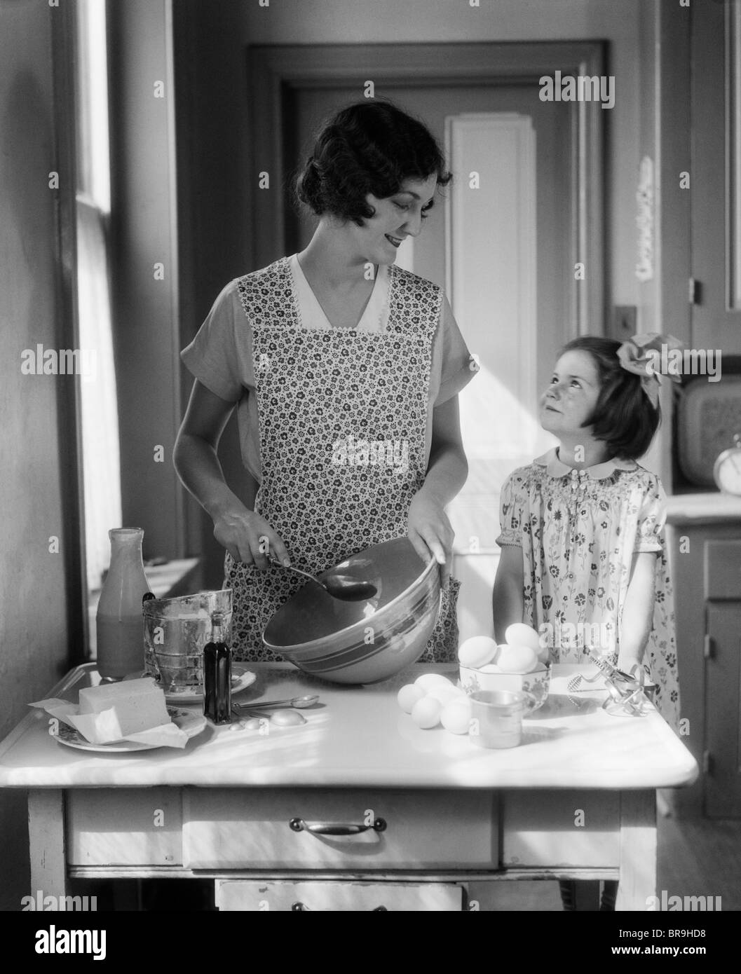 1920s 1930s MOTHER WITH MIXING BOWL IN KITCHEN WITH DAUGHTER Stock Photo -  Alamy