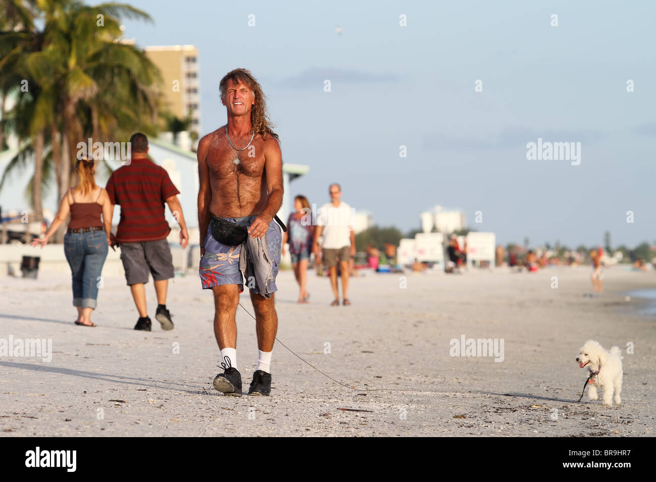 Shirtless handsome man walking with his dog by the sea Stock Photo