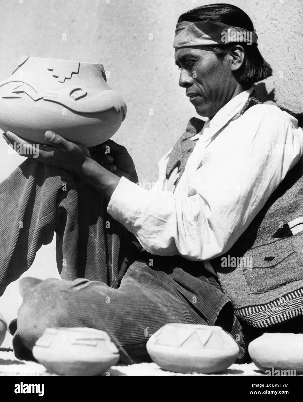 1930s PUEBLO INDIAN MAN HOLDING DECORATED POTTERY BOWL Stock Photo