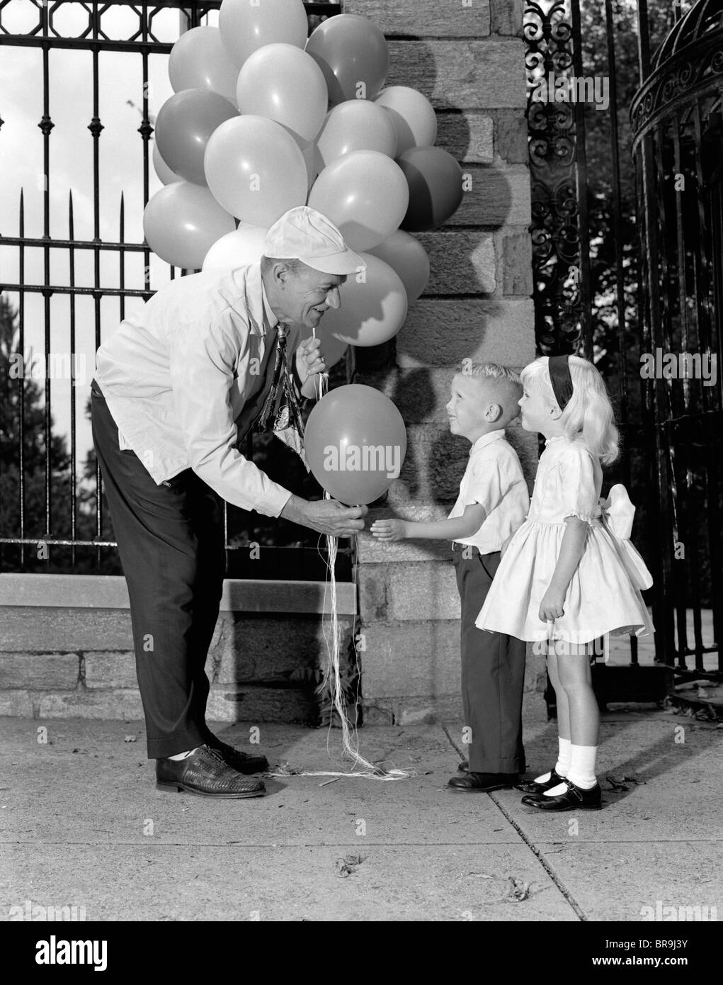 1960s CHILDREN BOY GIRL GETTING A BALLOON FROM MAN Stock Photo