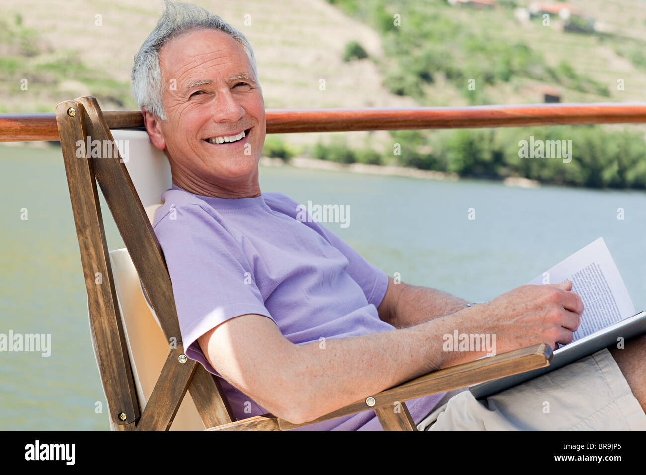 Senior man reading book on a boat holiday Stock Photo