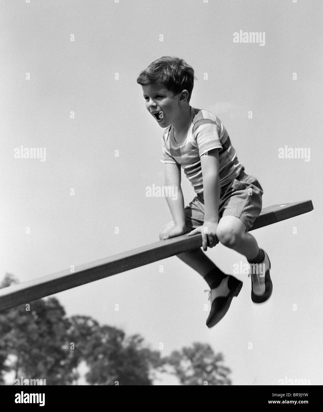 1930s 1940s EXCITED BOY ON SEESAW PLAYING Stock Photo