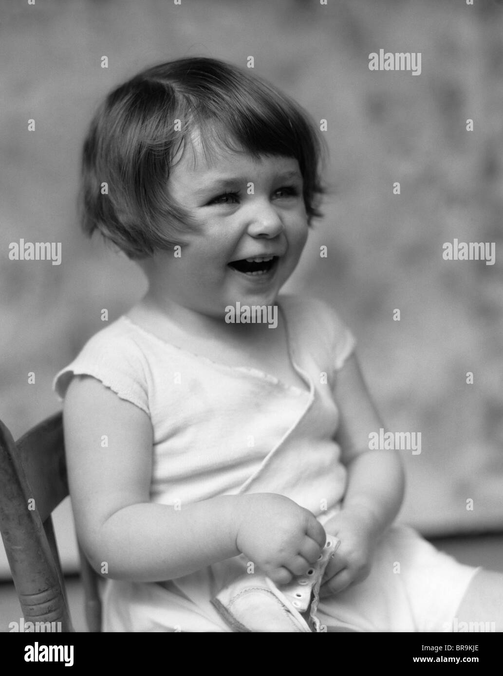 1930s SMILING LAUGHING TODDLER GIRL HOLDING SHOE Stock Photo