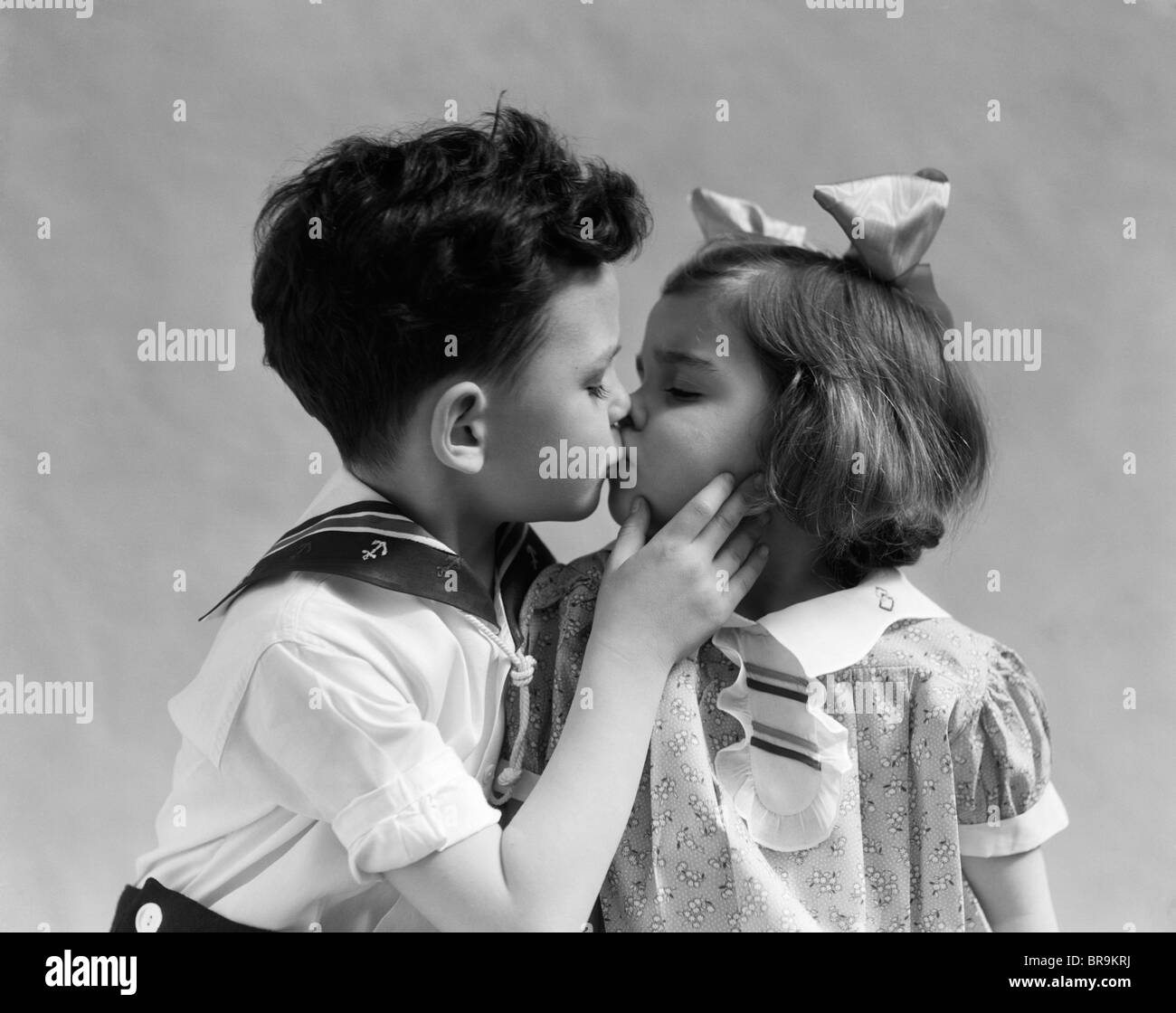 1930s TWO CHILDREN YOUNG BOY AND GIRL KISSING Stock Photo