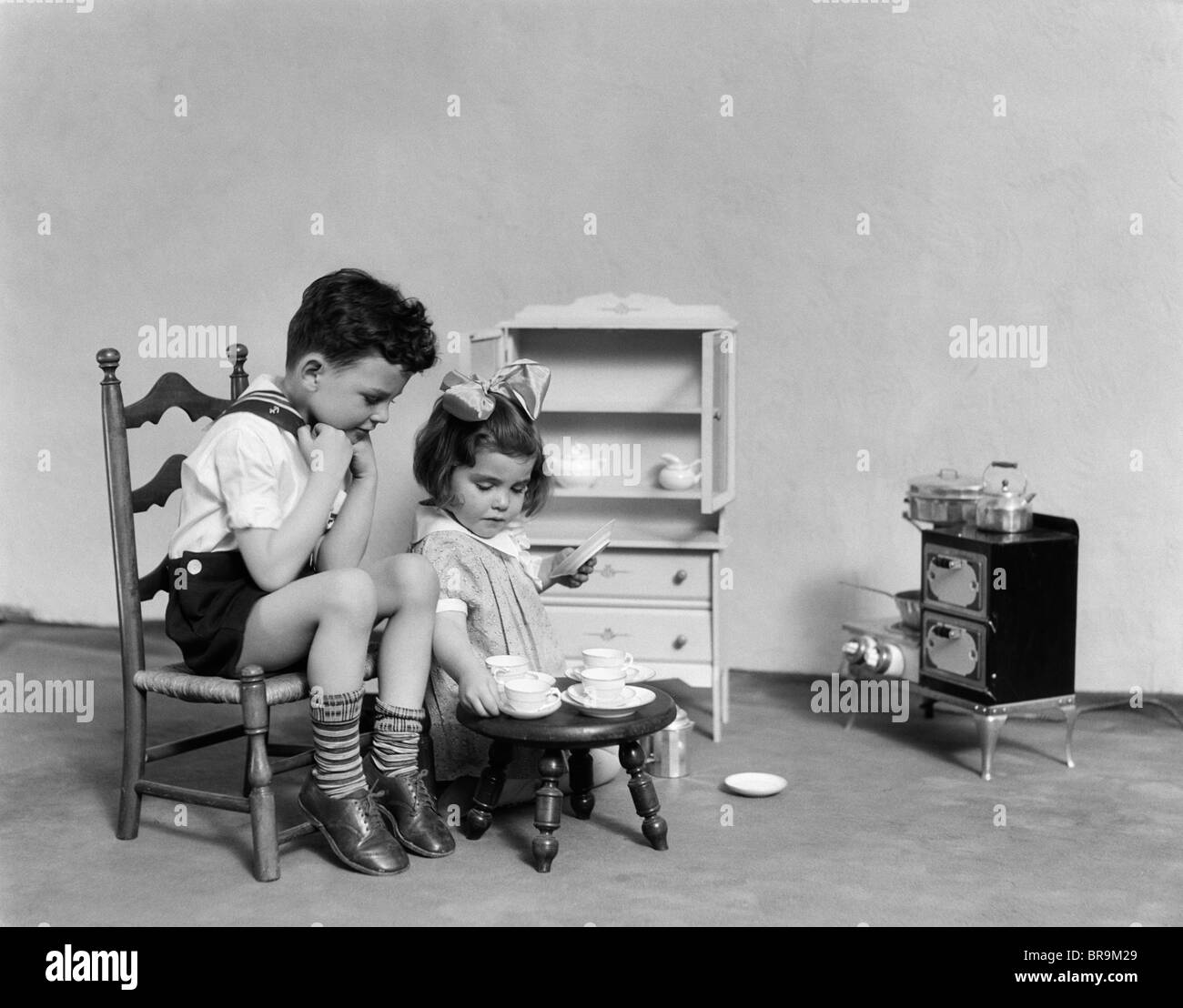 1930s TWO CHILDREN PLAYING HOUSE TEA PARTY Stock Photo
