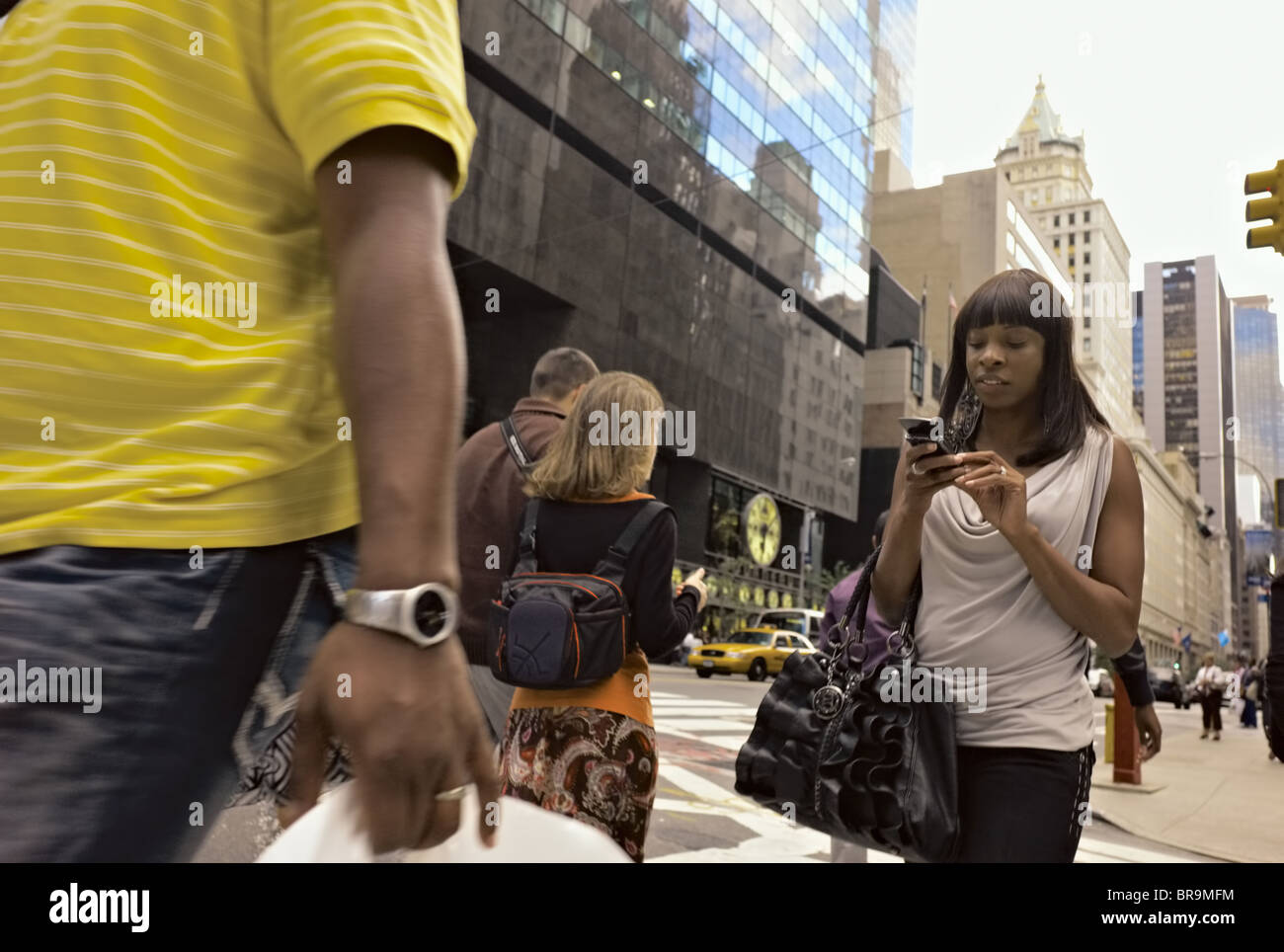 Woman walking across street while operating hand-held device. Stock Photo