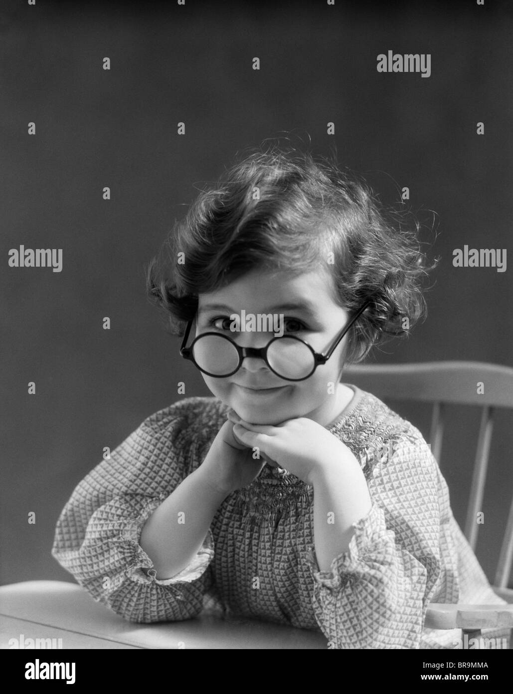 1930s PORTRAIT LITTLE GIRL SMILING WEARING BIG ROUND EYEGLASSES LOOKING AT CAMERA Stock Photo