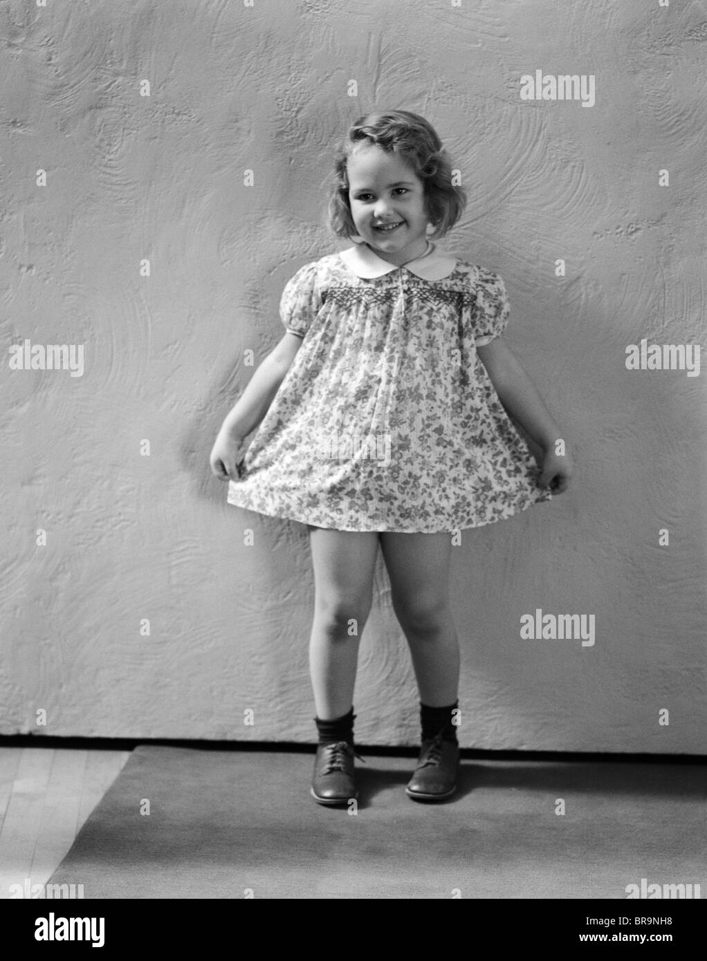 1940s LITTLE GIRL WEARING FLORAL PRINT DRESS READY TO TAKE A BOW Stock Photo