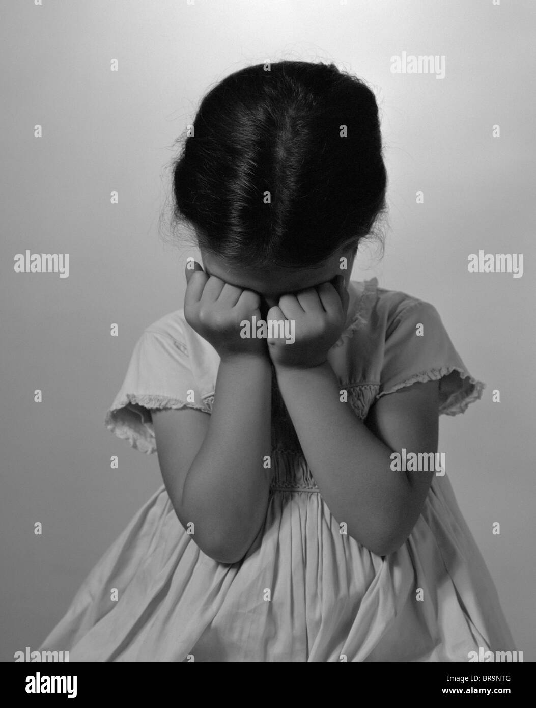 1960s LITTLE GIRL SITTING HANDS ON FACE SAD THINKING Stock Photo