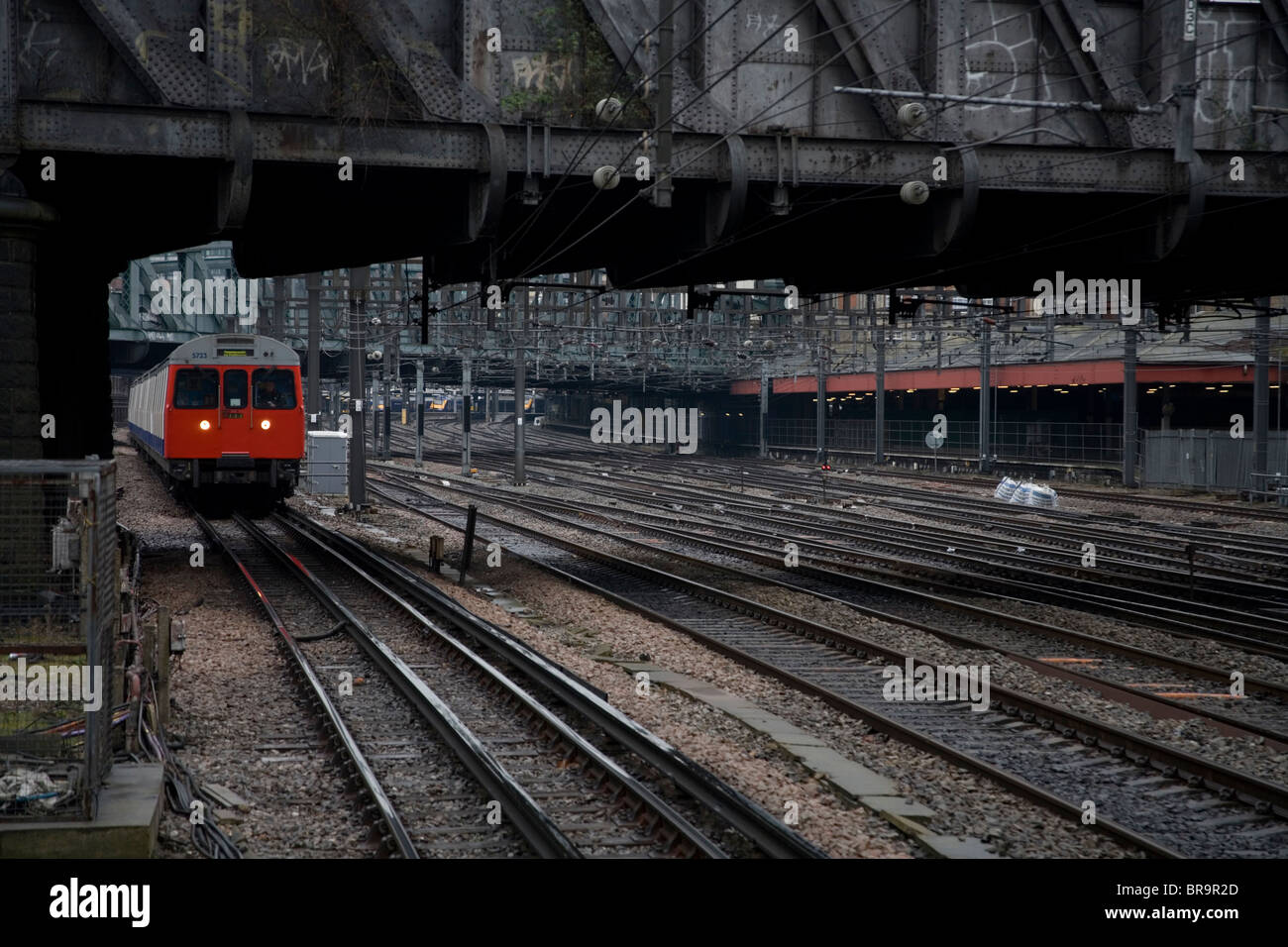 Tube train approaching Westbourne Park Station on tracks under bridge Stock Photo