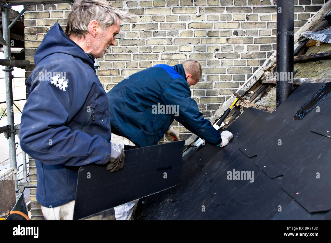 A plumber and his apprentice replace old leaky roof with new slates