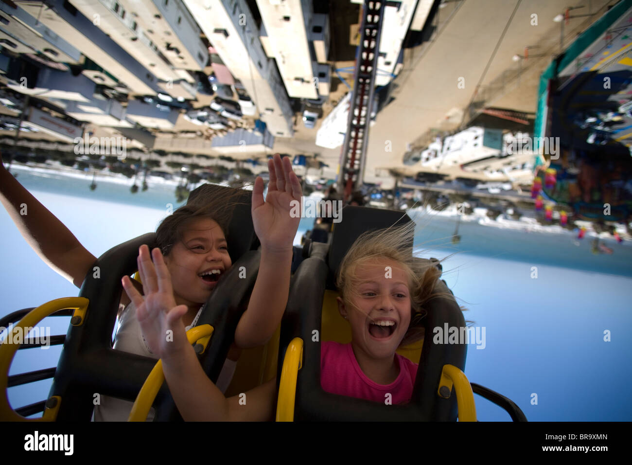 Two young girls scream upside down on a carnival ride at the Ventura County Fair. Stock Photo
