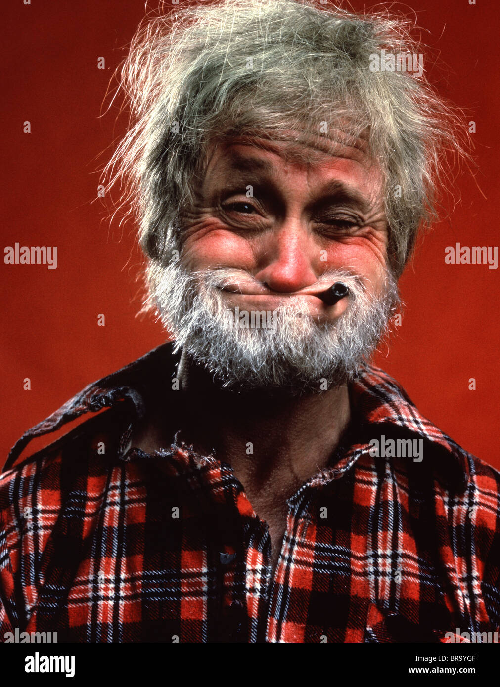 PORTRAIT OF MAN CHARACTER HILLBILLY GRAY HAIR BEARD FLANNEL SHIRT PIPE FUNNY HUMOROUS FACIAL EXPRESSION Stock Photo