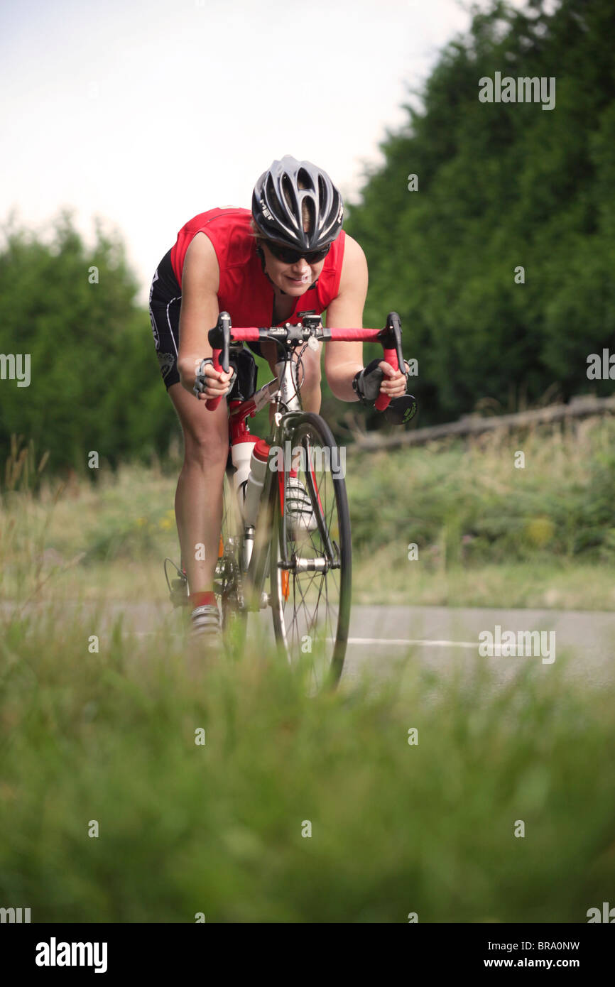 A woman on a road bike bending over her handle bars to pick up speed Stock  Photo - Alamy