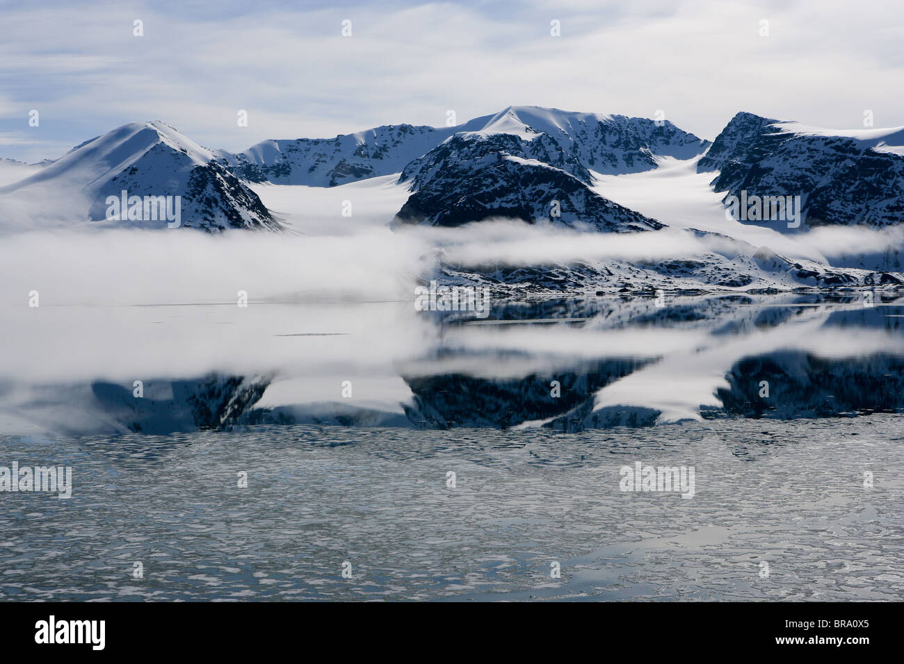 Snowy Mountains, Cloud and Crisp Reflections with Sea Ice, Liefdefjord, Svalbard, Arctic Norway Stock Photo