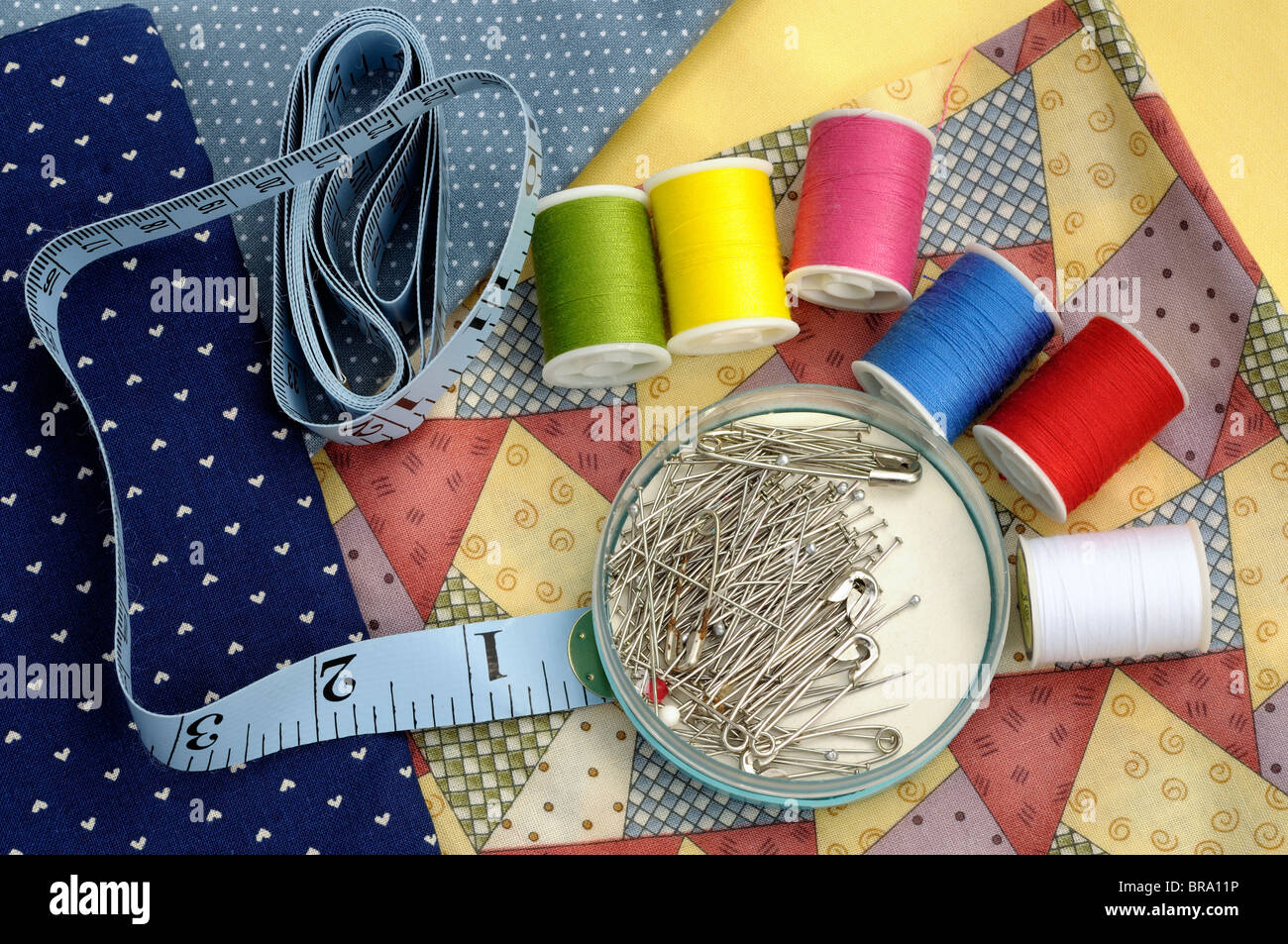 sewing accessories on background of coloured fabrics Stock Photo