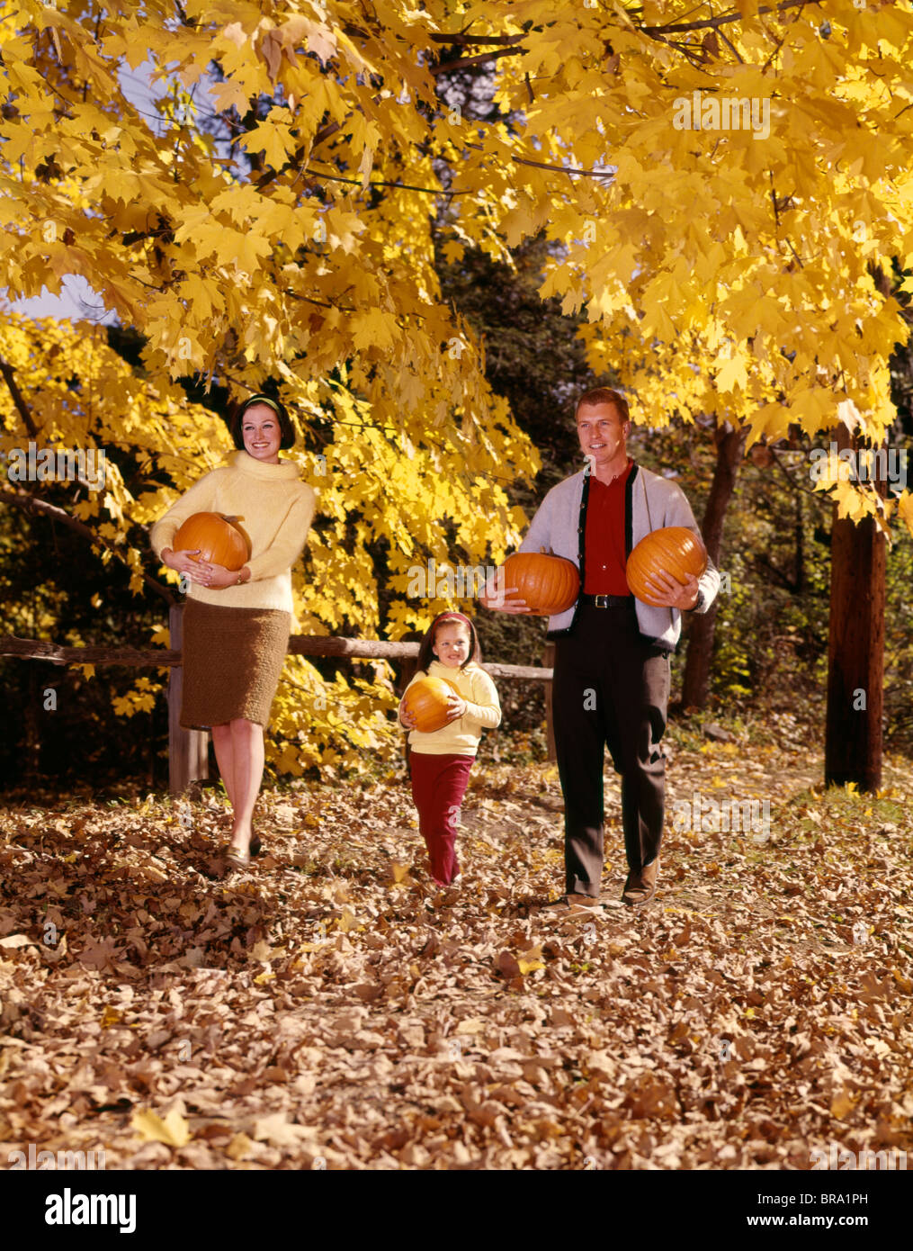 1960s SMILING FAMILY TRIO FATHER MOTHER DAUGHTER WALKING IN AUTUMN ...