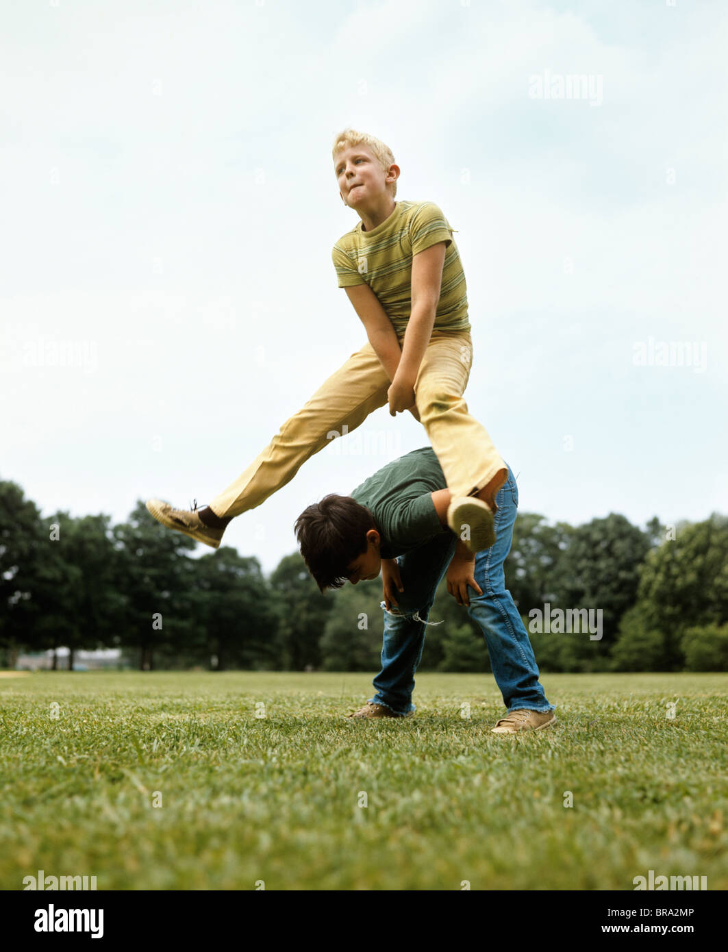 1970s TWO BOYS JUMPING PLAYING LEAPFROG LEAP FROG RETRO Stock Photo