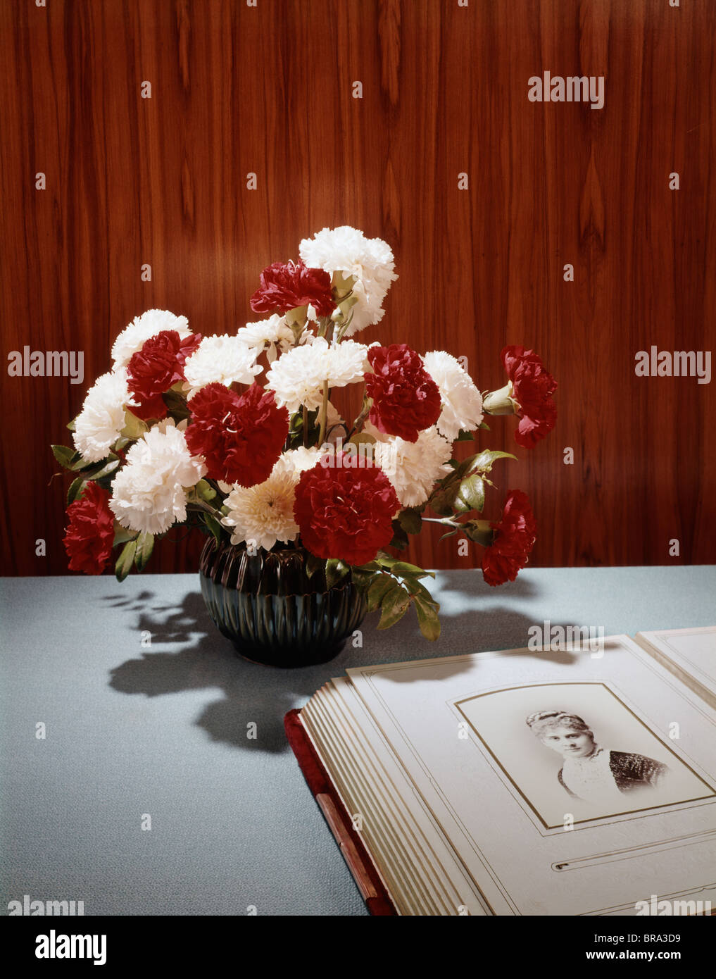 1960s STILL LIFE BOUQUET RED WHITE CARNATIONS ANTIQUE FAMILY ALBUM PHOTO OF WOMAN RETRO Stock Photo