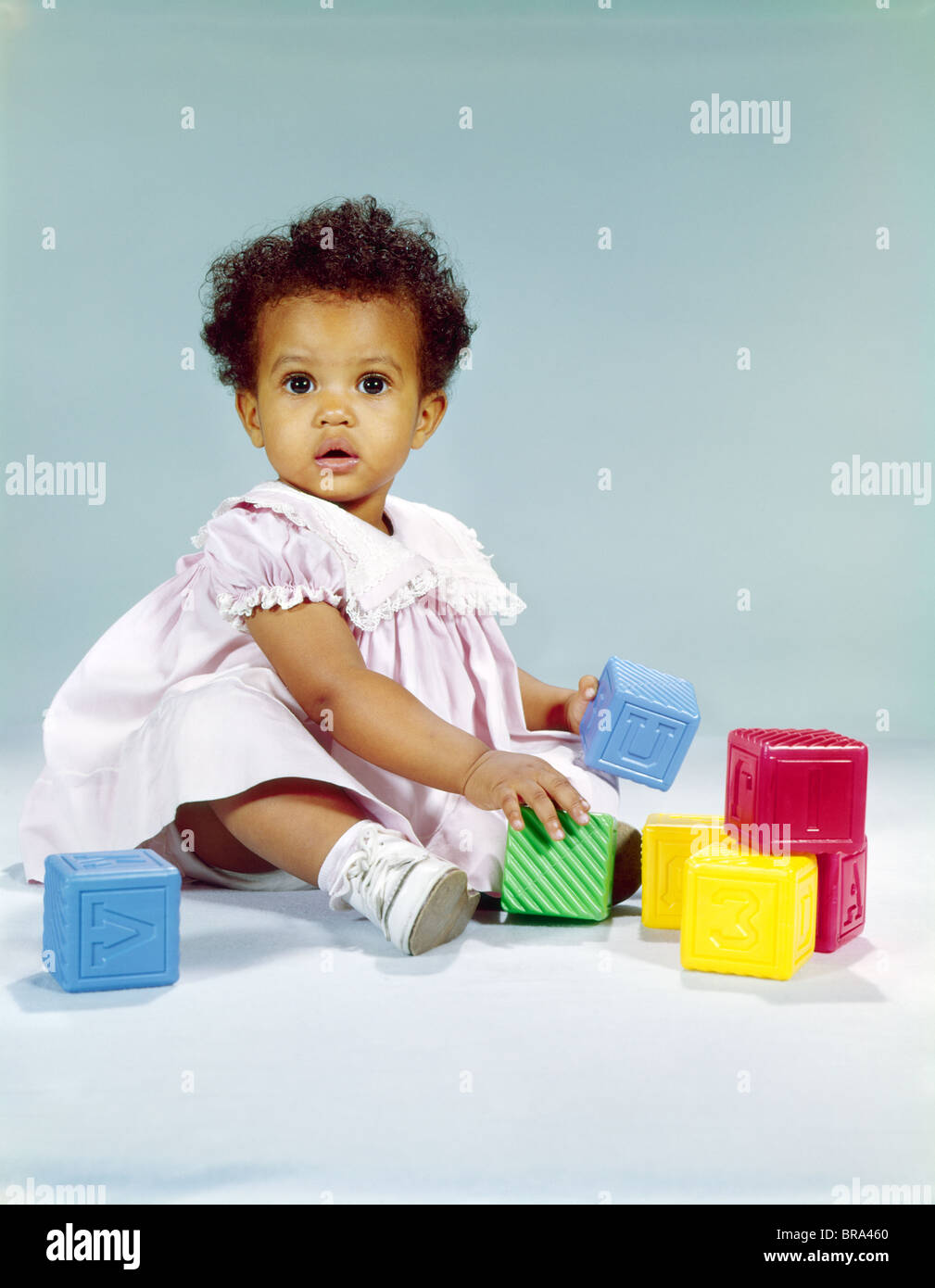 1960s AFRICANAMERICAN BABY GIRL TODDLER IN PINK DRESS PLAYING WITH TOY
