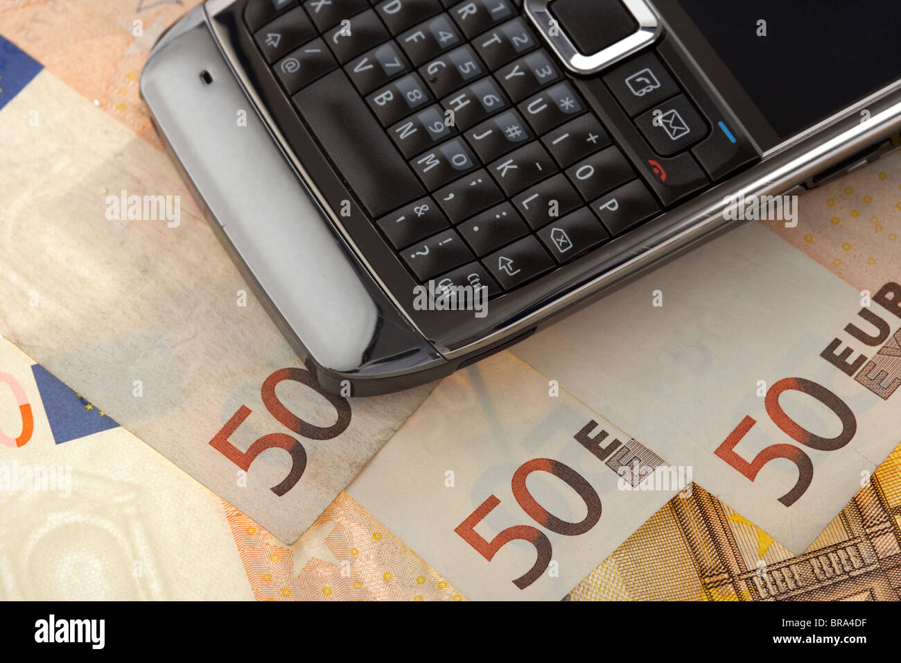 mobile cell phone smartphone on a pile of 50 euro banknotes Stock Photo