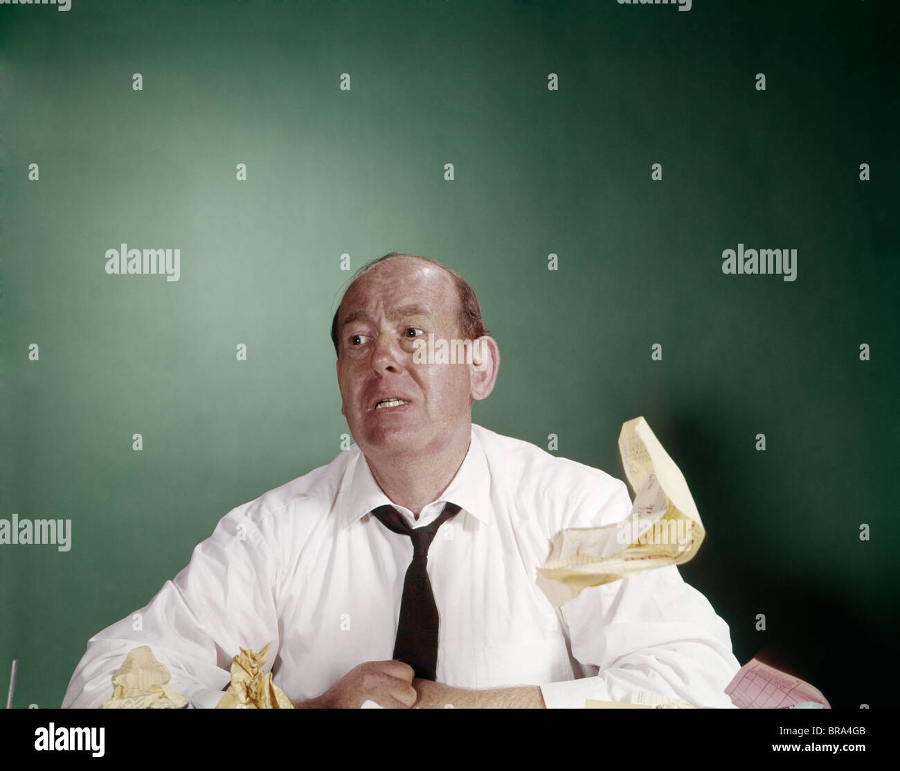 1960s TIRED OVERWORKED BUSINESSMAN AT DESK SHIRTSLEEVES LOOSE TIE PAPER FLOATING RETRO FUNNY