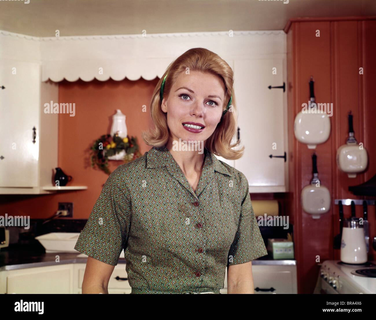 1960s PORTRAIT YOUNG BLONDE WOMAN IN KITCHEN SMILING RETRO Stock Photo