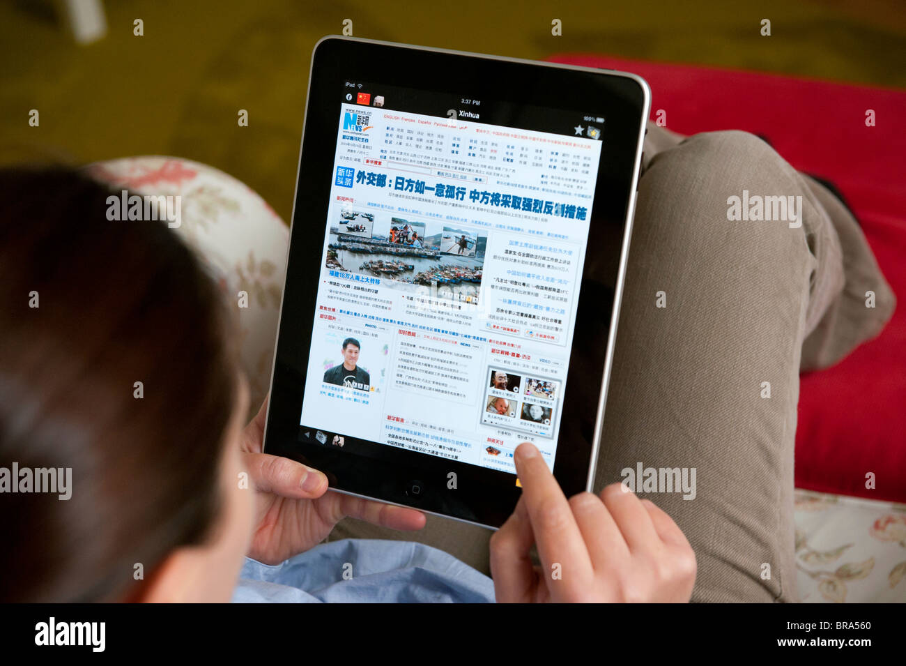 Woman using iPad tablet computer at home to read Xinhua Chinese newspaper Stock Photo