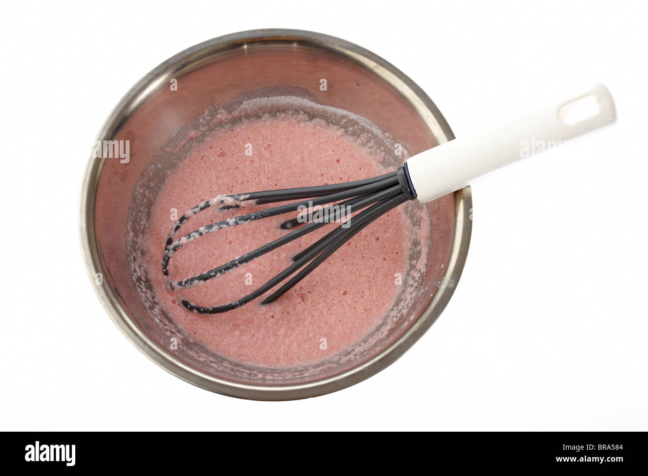 using a whisk to make angel delight dessert in a mixing bowl cutout on a white background Stock Photo