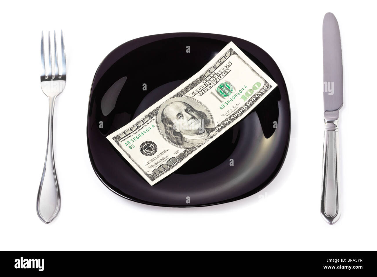 One hundred dollar banknote on a black plate with knife and fork Stock Photo