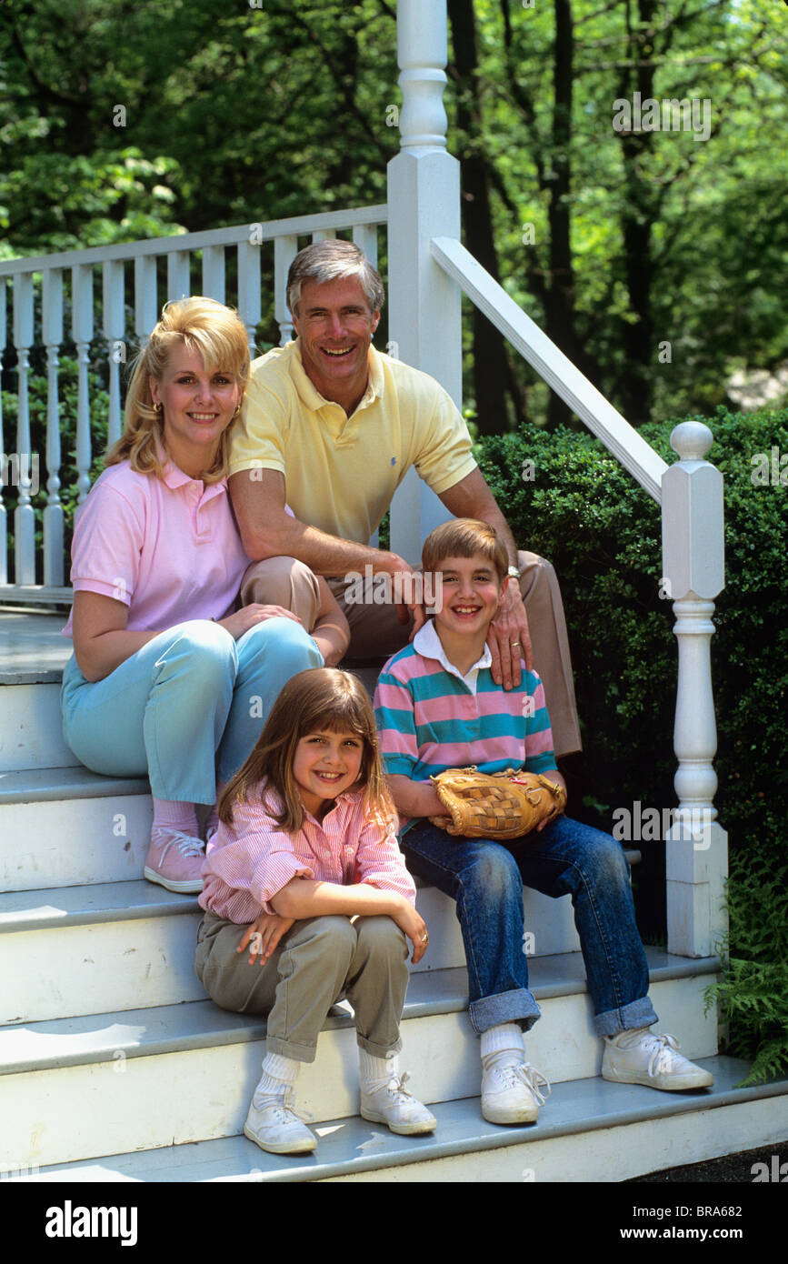 1980 1980s RETRO PARENTS CHILDREN FAMILY SITTING PORCH STEPS SMILING MOTHER FATHER SON DAUGHTER Stock Photo