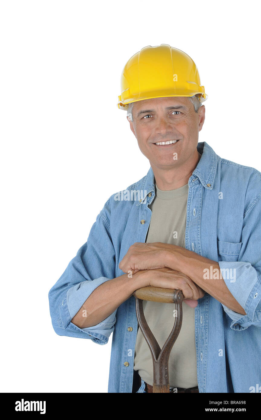 Workman leaning on the handle of his shovel. Man is wearing a hard hat and smiling at the camera. Stock Photo