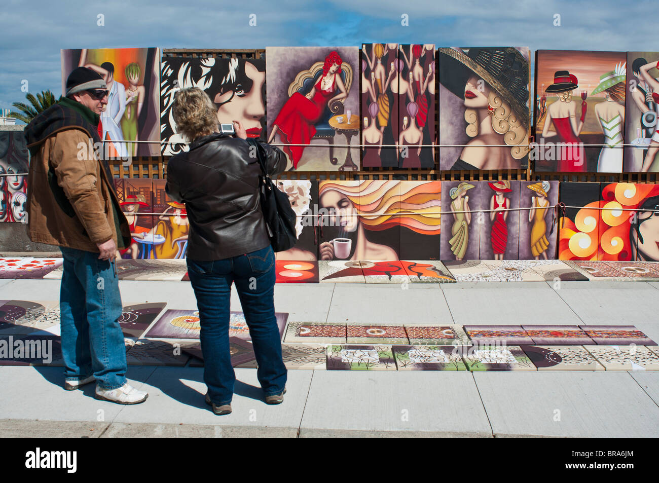 Artist displaying painting to a potential customer at the St Kilda