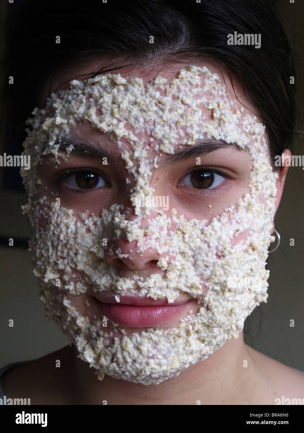 Teenage girl using an oatmeal mask to cleanse her skin Stock Photo