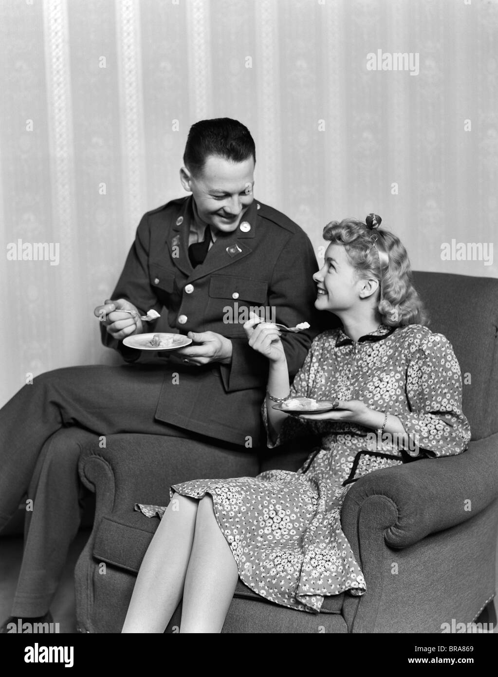 1940s SMILING COUPLE EATING DESSERT MAN IN ARMY UNIFORM Stock Photo