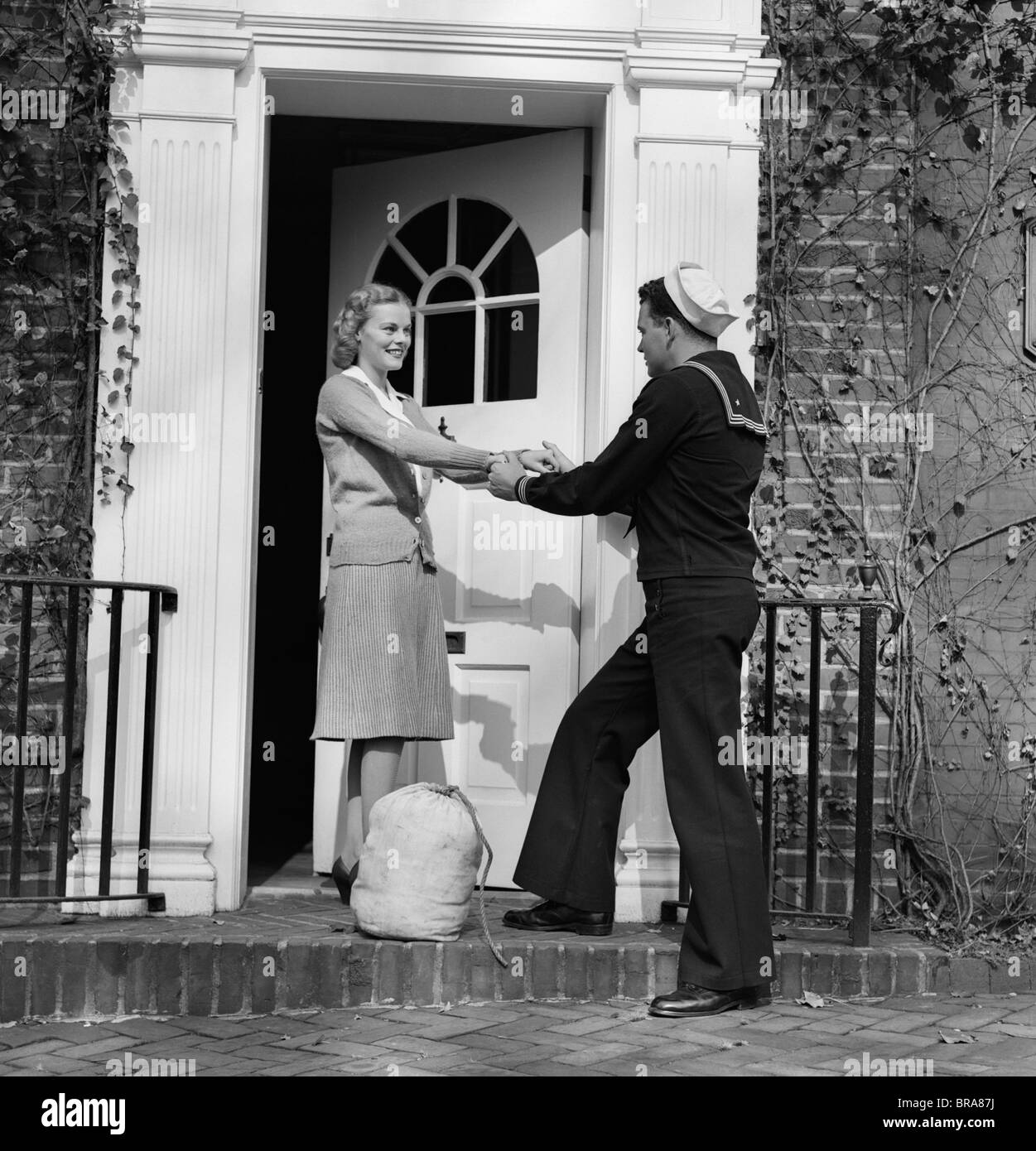 1940s WOMAN GREETING MAN SAILOR AT FRONT DOOR Stock Photo