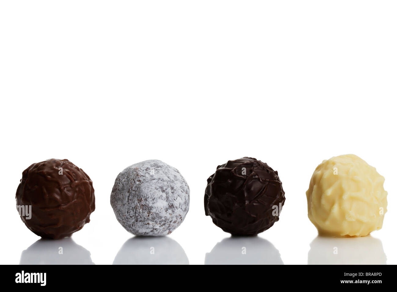 four different truffle pralines in a row on white background Stock Photo