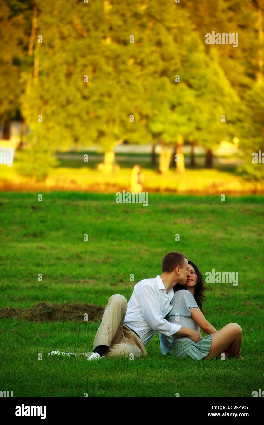 young couple sitting on park lawn and embrace Stock Photo - Alamy