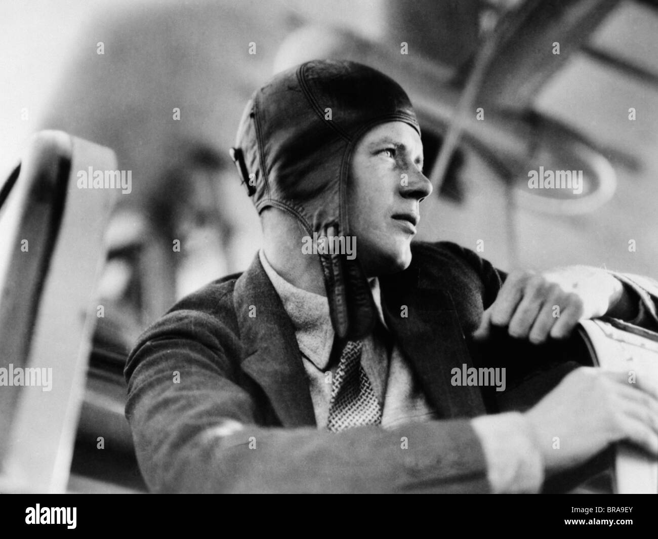1920s CLOSE-UP OF CHARLES LINDBERGH IN LEATHER AVIATOR CAP SITTING IN COCKPIT OF PLANE Stock Photo