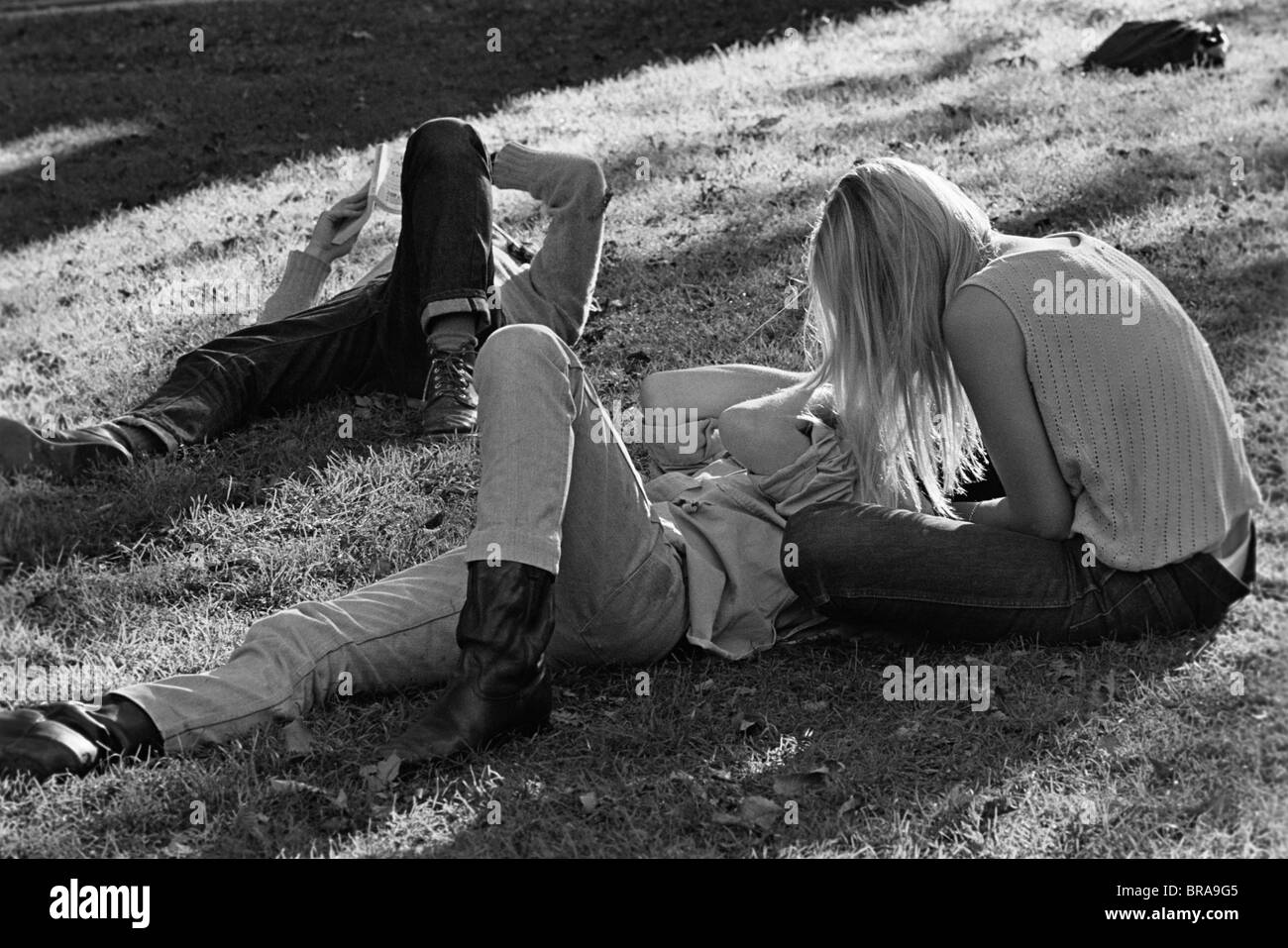 1960s 1970s HIPPIE COUPLE WOMAN WITH LONG BLONDE HAIR SIT BESIDE MAN LYING IN GRASS Stock Photo