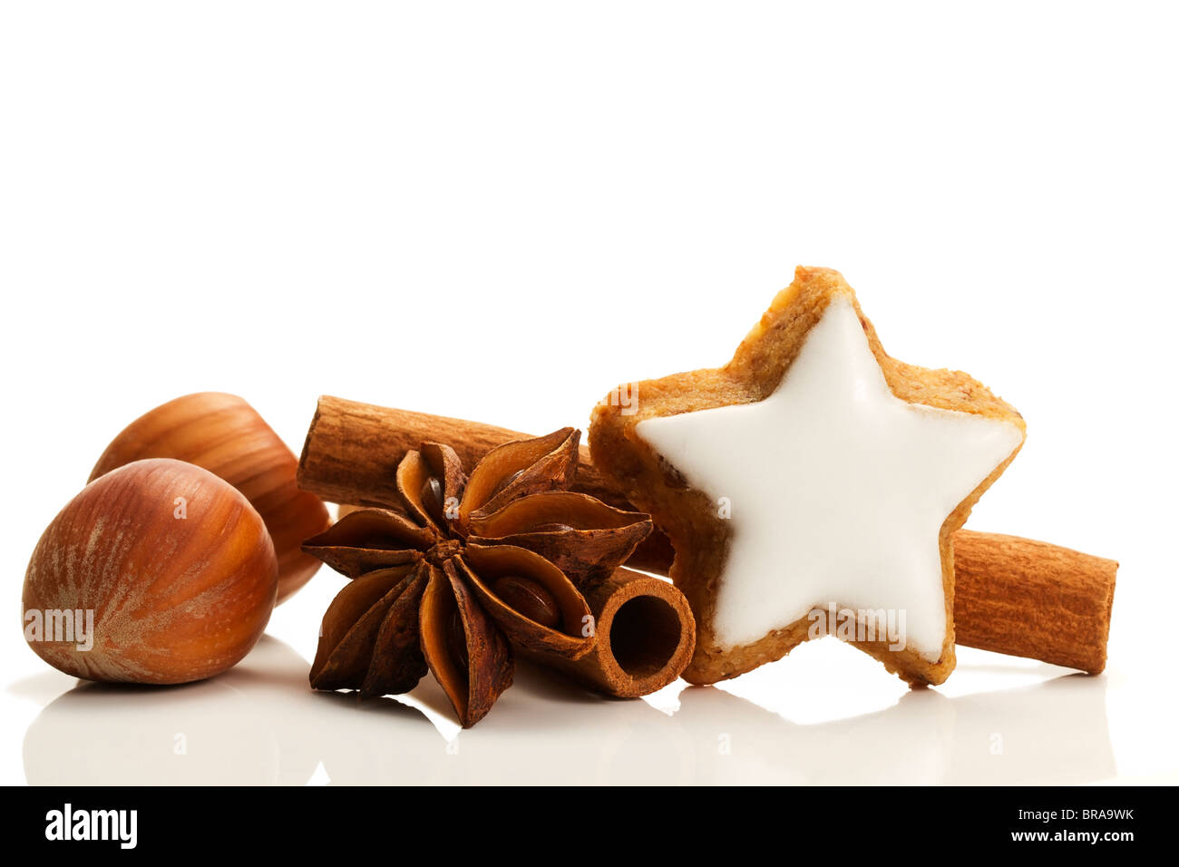 star shaped cinnamon biscuit with cinnamon sticks and hazelnuts on white background Stock Photo