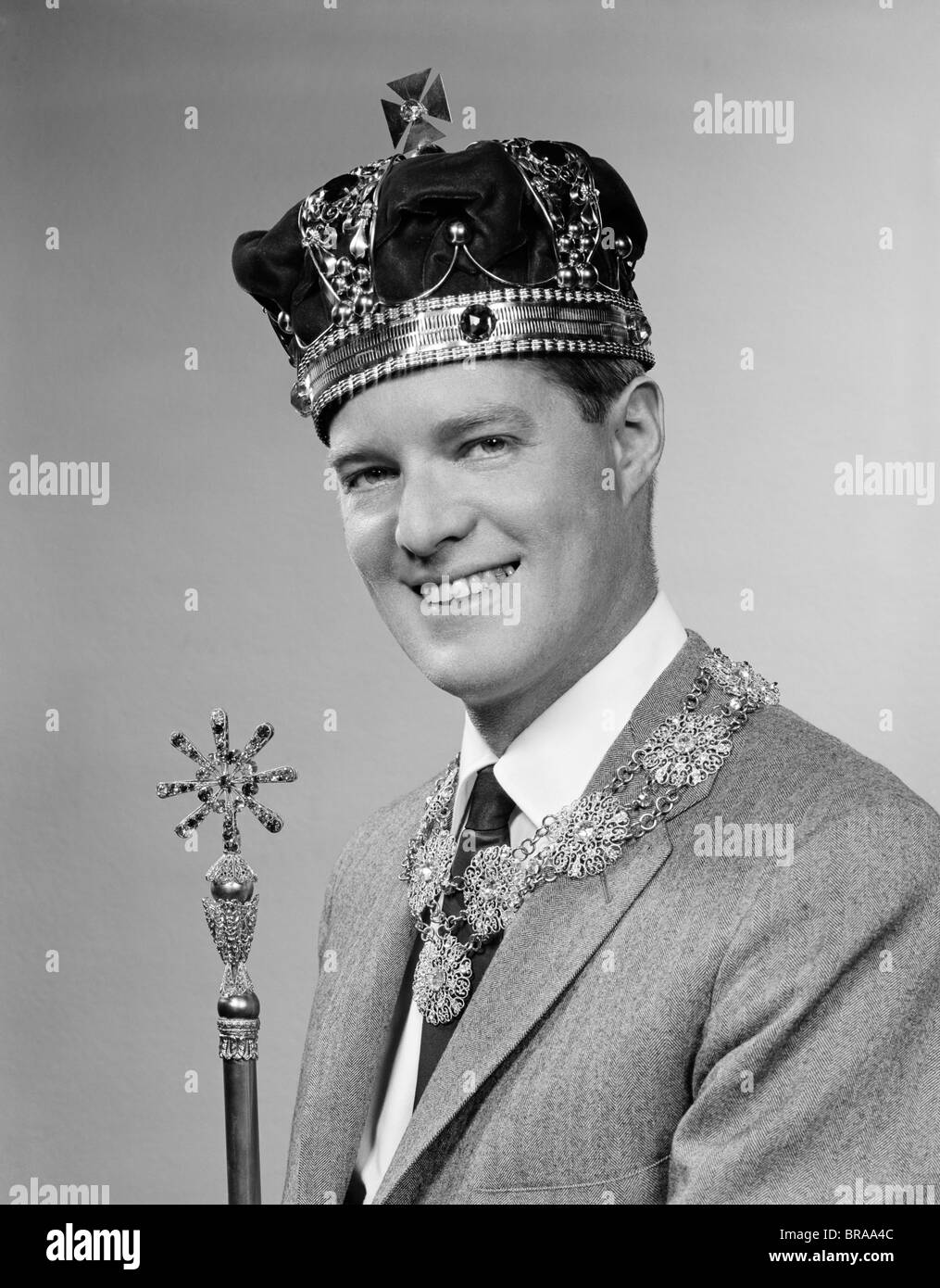 1950s PORTRAIT OF MAN WEARING A KING'S CROWN AND HOLDING A SCEPTER WHILE SMILING Stock Photo