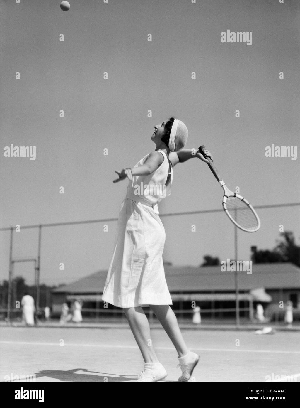 1930s WOMAN PLAYING TENNIS ABOUT TO HIT BALL WITH RACKET Stock Photo